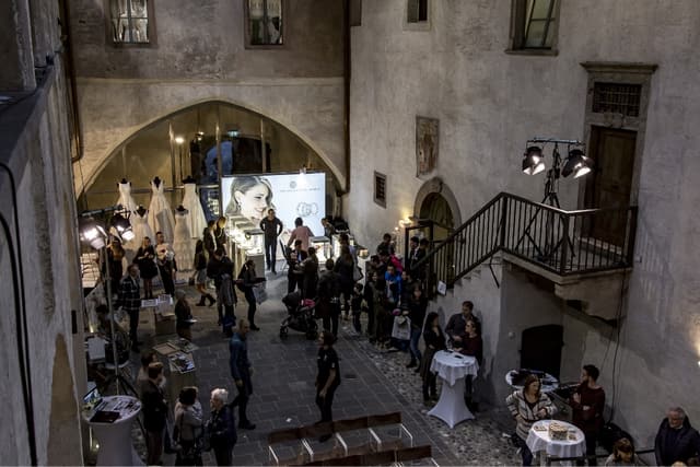 Besucher im abendlich beleuchteten Innenhof von Schloss Maretsch zwischen Brautkleidern und Ausstellern